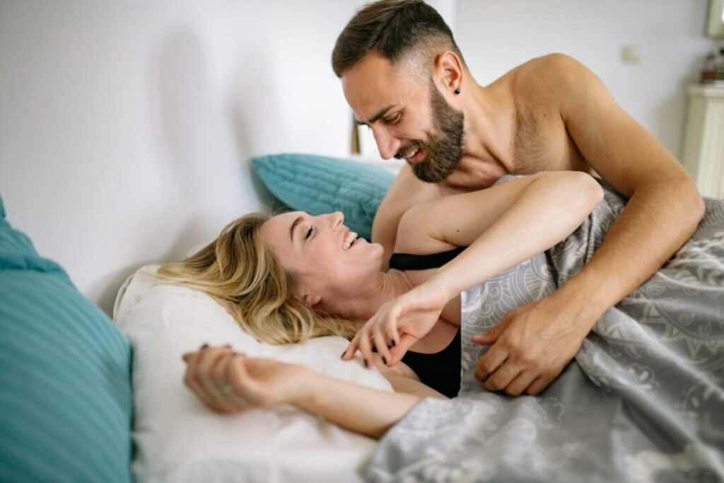 happy guy and girlfriend laying in bed